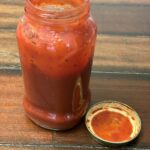 Red Sauce in a jar sitting on a wooden surface