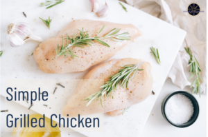 Uncooked chicken breast on a cutting board with rosemary on top.