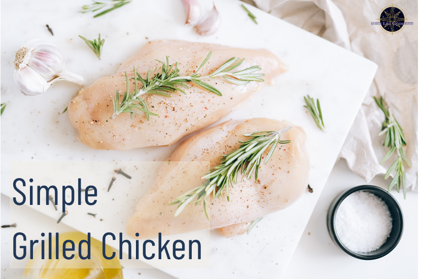 Uncooked chicken breast on a cutting board with rosemary on top.